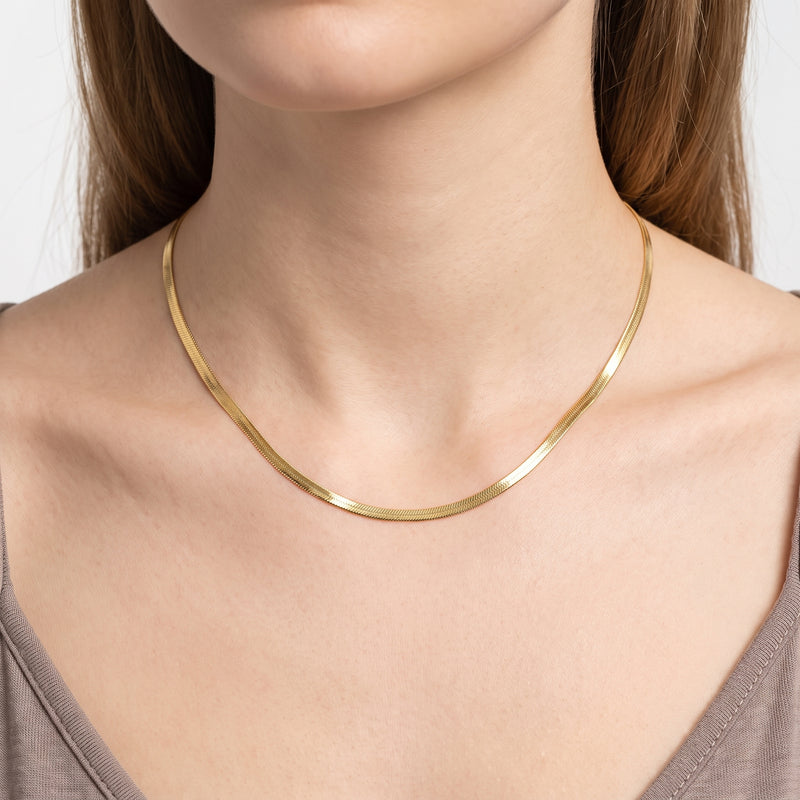 Close-up of the Lelice Harper Herringbone Necklace in gold at the collarbone