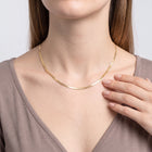 Hand at the collar of a woman wearing the Harper Herringbone Necklace