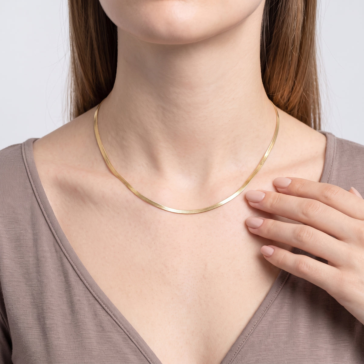 Hand at the collar of a woman wearing the Harper Herringbone Necklace