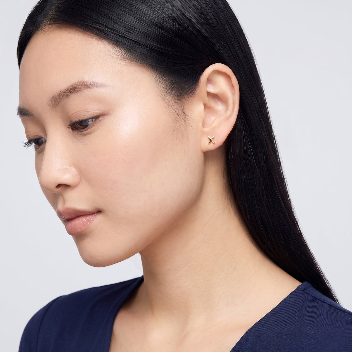 Model wearing the Lelice Holly Stud Earrings in gold, downcast beauty portrait