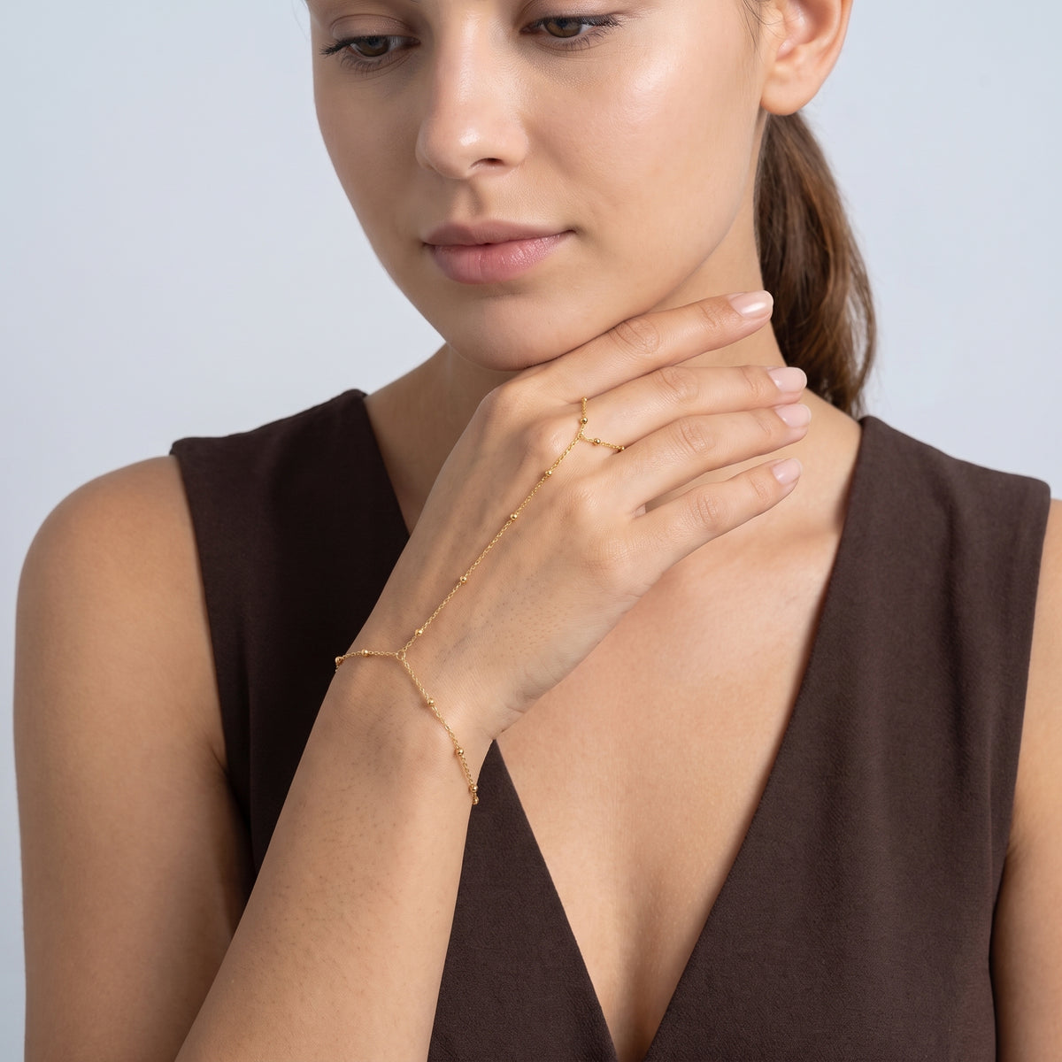 Model wearing the Lelice Inès Chain Bracelet in gold, chin resting on the hand