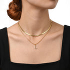 Close-up of the Lelice Initial Herringbone Necklace in gold at the collarbone
