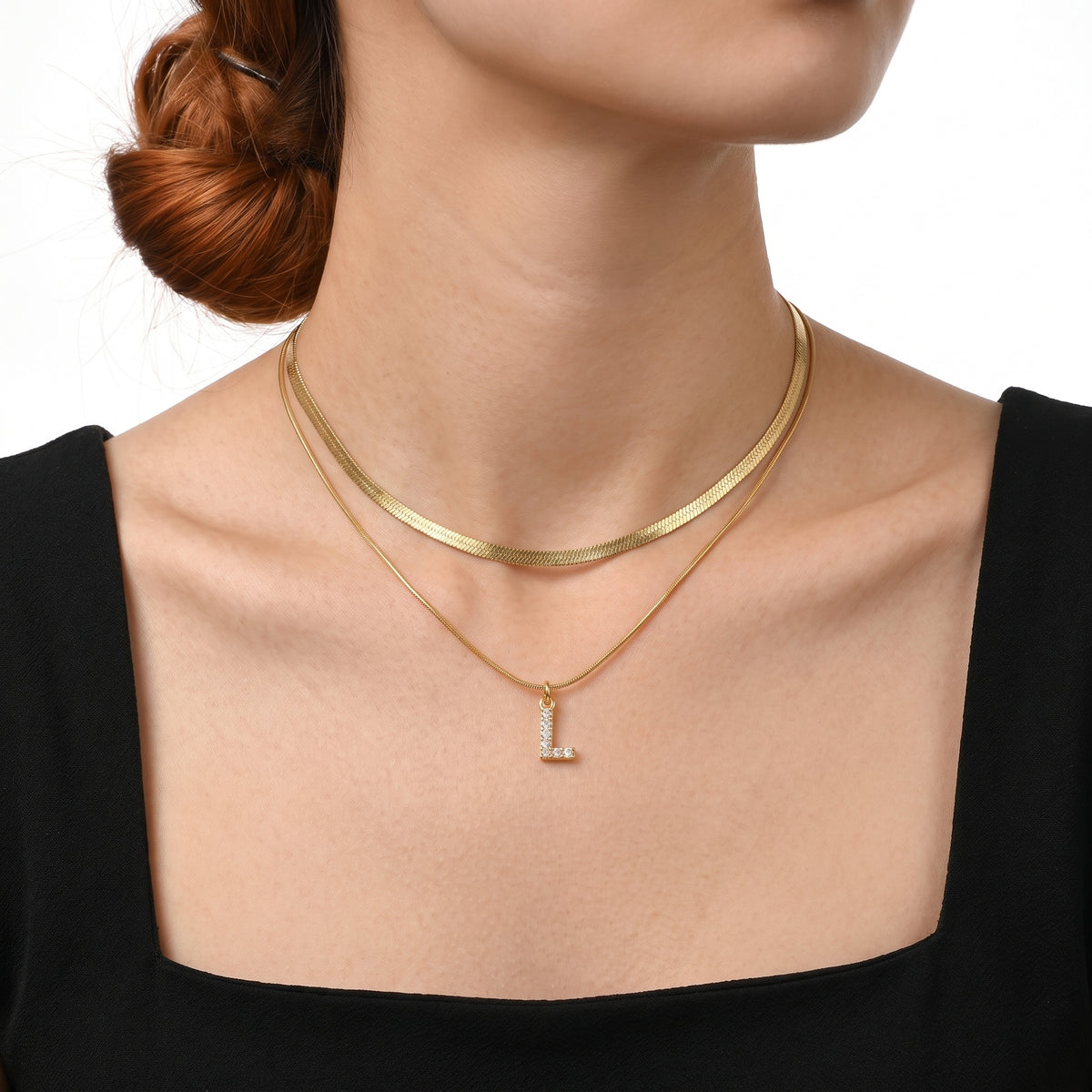 Close-up of the Lelice Initial Herringbone Necklace in gold at the collarbone