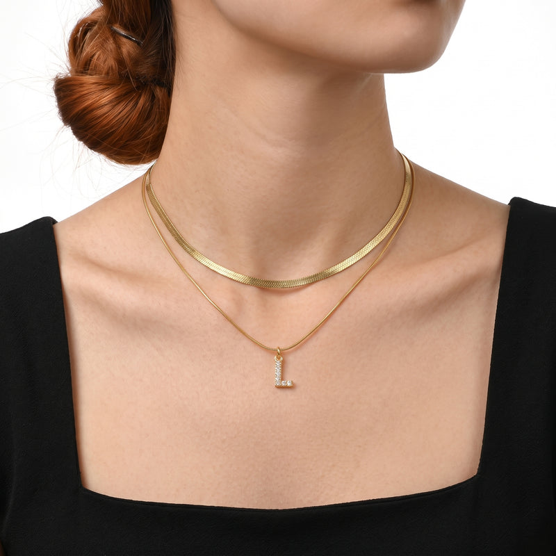 Close-up of the Lelice Initial Herringbone Necklace in gold at the collarbone