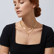 Low-angle portrait of a woman wearing the Initial Herringbone Necklace