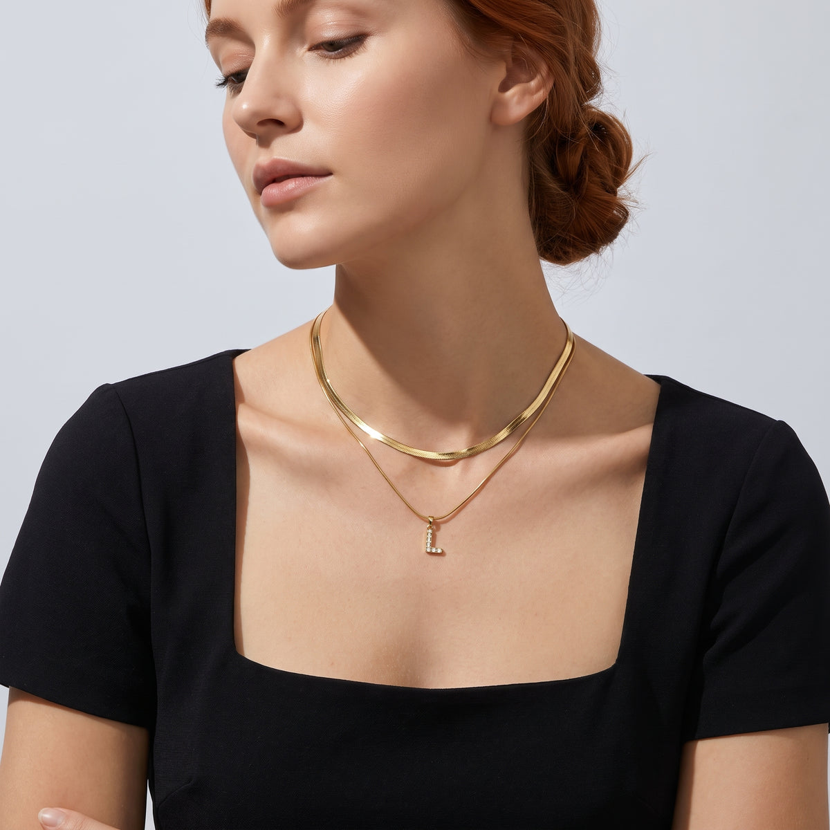 Low-angle portrait of a woman wearing the Initial Herringbone Necklace