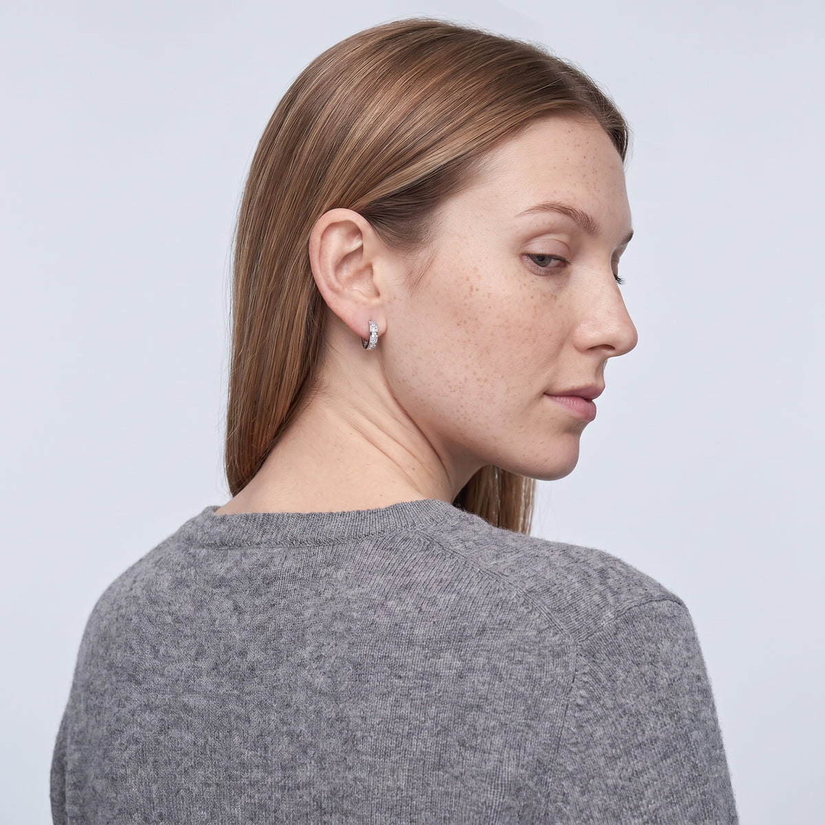 Model wearing the Lelice Isla Silver Square Crystal Huggie Hoop Earrings, over-the-shoulder glance