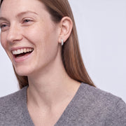 Model wearing the Lelice Isla Silver Square Crystal Huggie Hoop Earrings, candid laugh