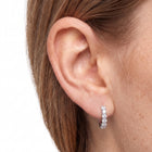Close-up of ear wearing Lelice silver crystal huggie hoop earrings Julia