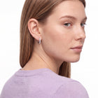 Woman glancing over her shoulder wearing Julia silver crystal huggies