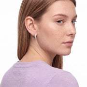 Woman glancing over her shoulder wearing Julia silver crystal huggies
