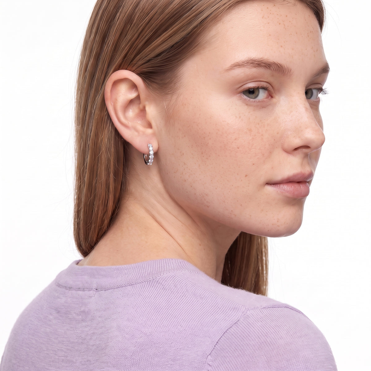 Woman glancing over her shoulder wearing Julia silver crystal huggies