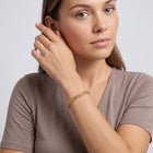 Model wearing the Lelice Armor Gold Bracelet, hand at the face