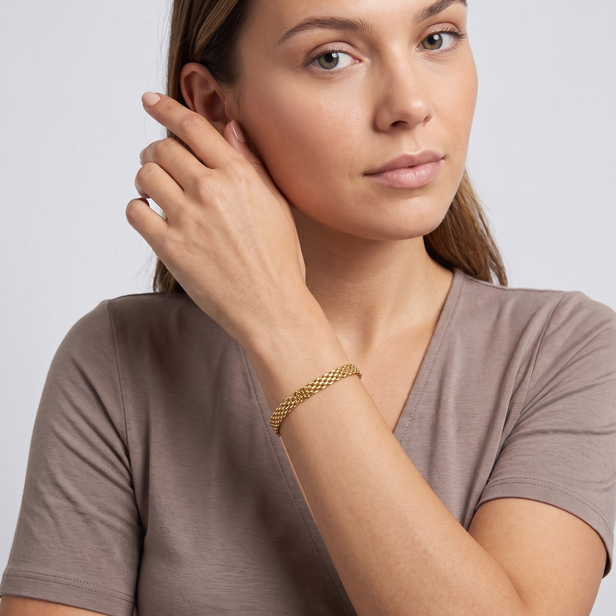 Model wearing the Lelice Armor Gold Bracelet, hand at the face