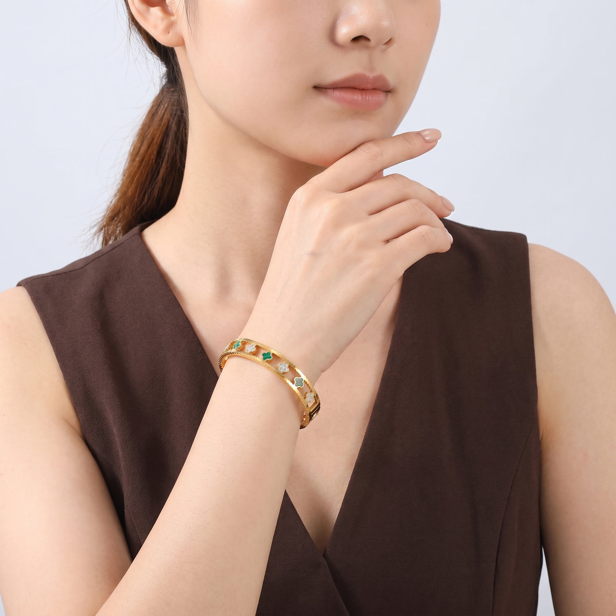 Model wearing the Lelice Dublin Quatrefoil Gold Bangle, chin resting on the hand