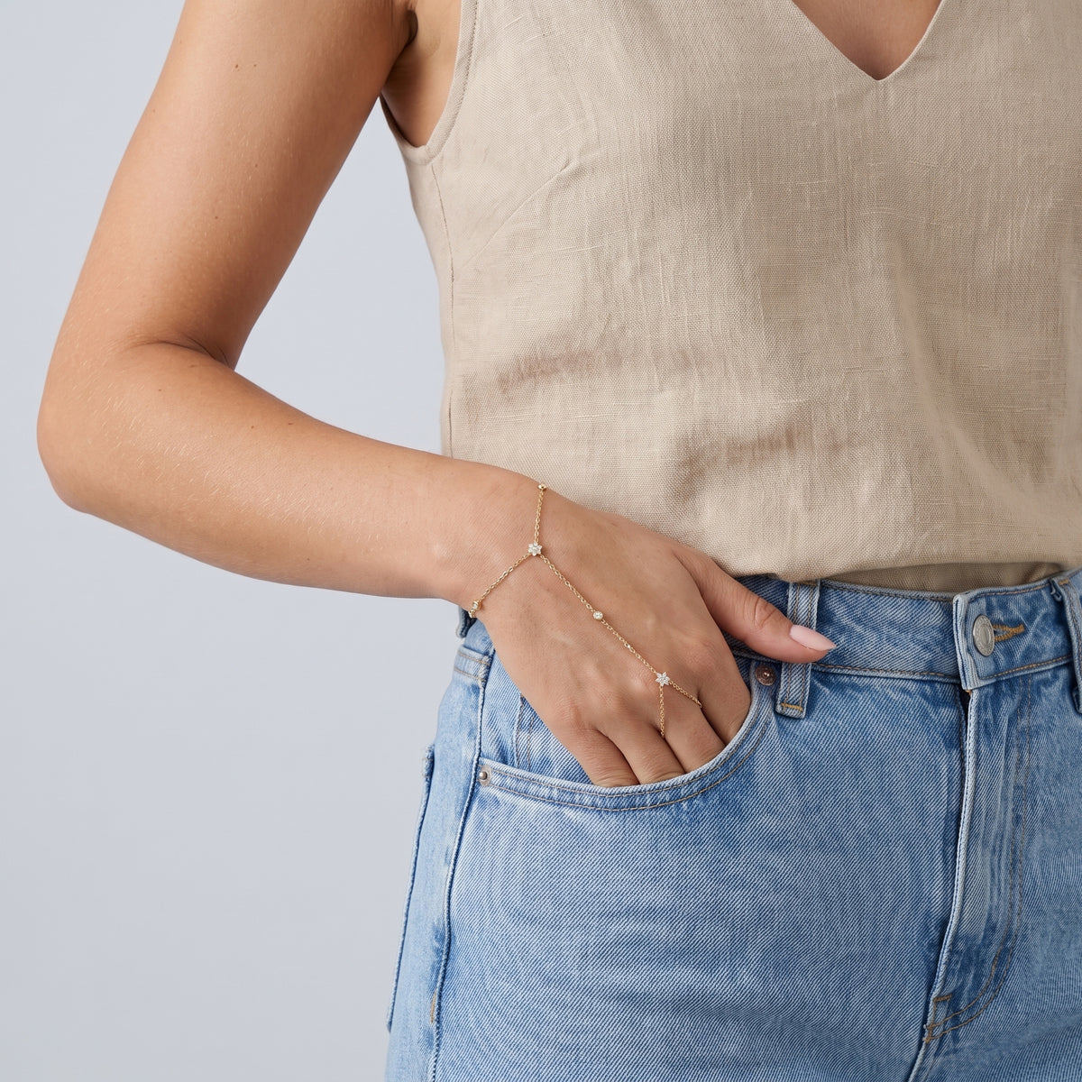 Model wearing the Lelice Lyra Crystal Hand Chain in gold, hand in the jeans pocket