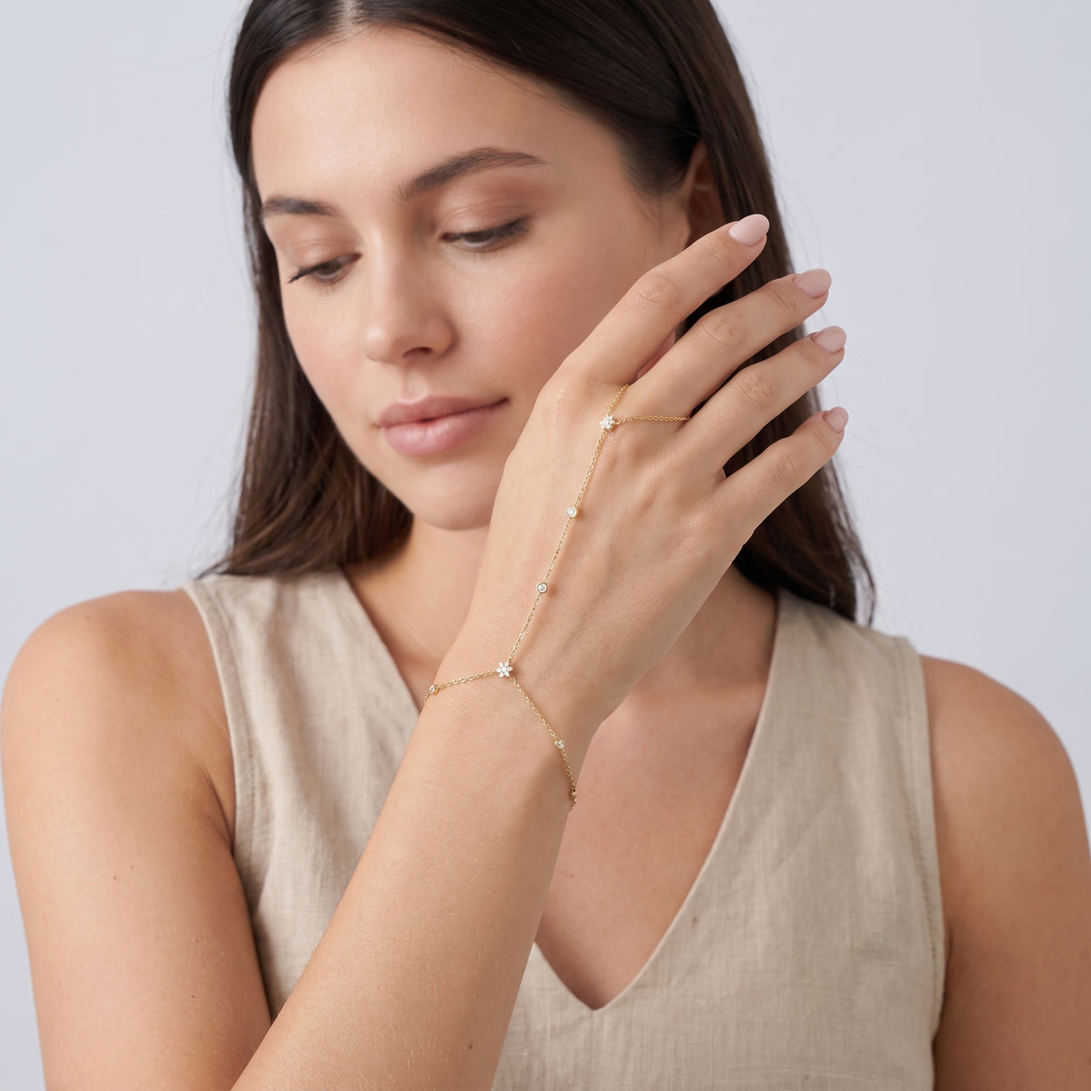 Model wearing the Lelice Lyra Crystal Hand Chain in gold, hand in front of the face