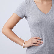 Model wearing the Lelice Lyra Cuff Bangle in gold, hand on the hip