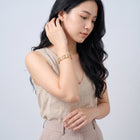 Model wearing the Lelice Miya Gold Clover Bangle, sweeping hair over the shoulder