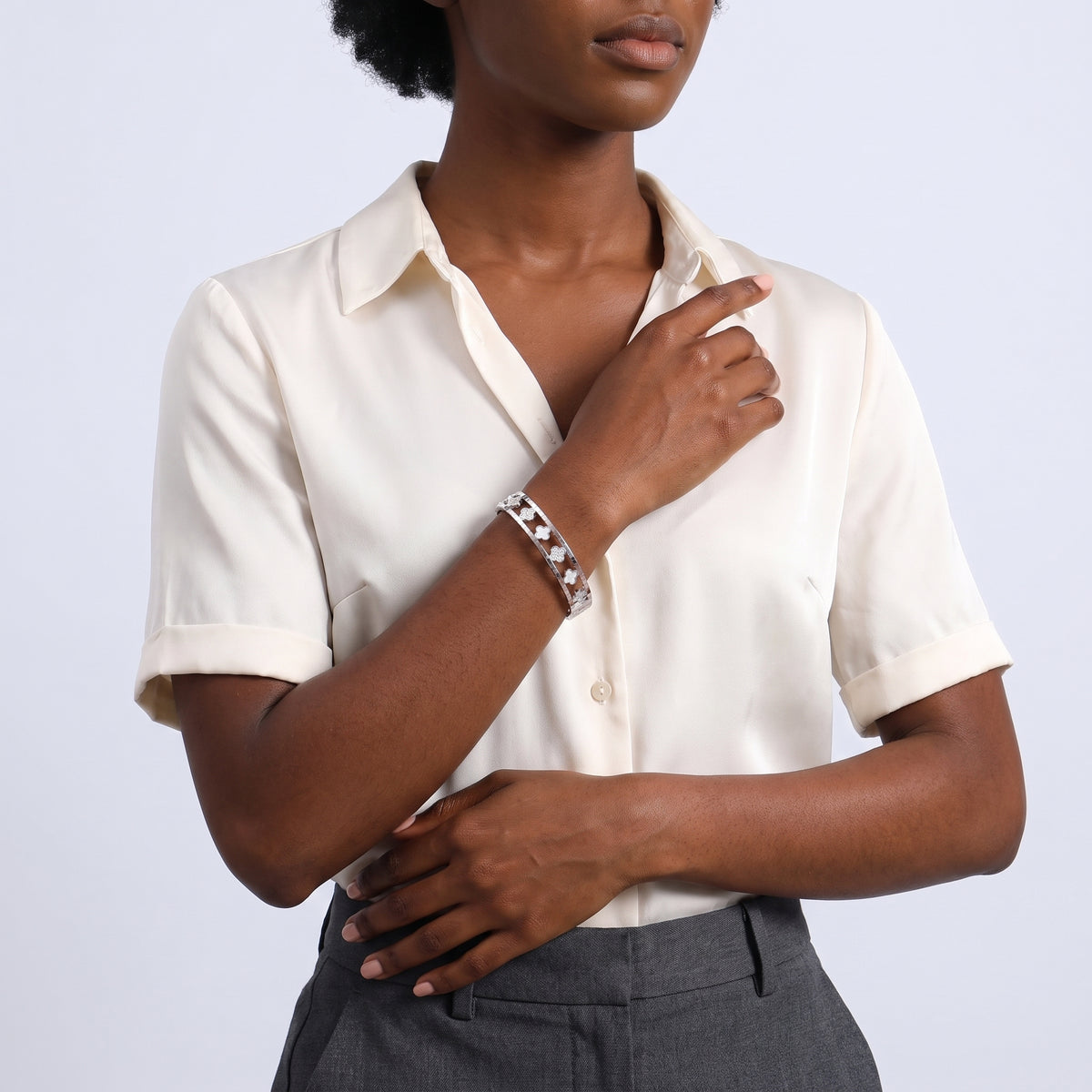 Model wearing the Lelice Miya Silver Clover Bangle, hand resting at the waist