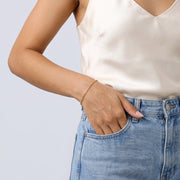 Model wearing the Lelice Modern Paperclip Bracelet in gold, hand in the jeans pocket