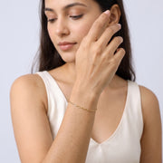 Model wearing the Lelice Modern Paperclip Bracelet in gold, hand in front of the face