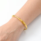 Close-up of the Lelice Sahara Wave Bangle in gold on the wrist