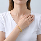 Model wearing the Lelice Sahara Wave Bangle in gold, hand across the chest