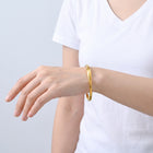 Model wearing the Lelice Sahara Wave Bangle in gold, forearm across the frame, hand relaxed