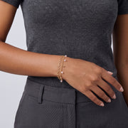 Model wearing the Lelice Lola Charm Bracelet in gold, hand resting at the waist