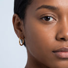 Model wearing the Lelice Lucy Round Hoops in gold, one-eye face close-up