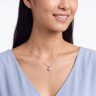 Woman with head tilted down wearing Marianne silver solitaire necklace
