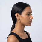 Model wearing the Lelice Maya Hoop Earrings in gold, slicked-back profile