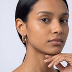 Model wearing the Lelice Maya Hoop Earrings in gold, hand at the chin