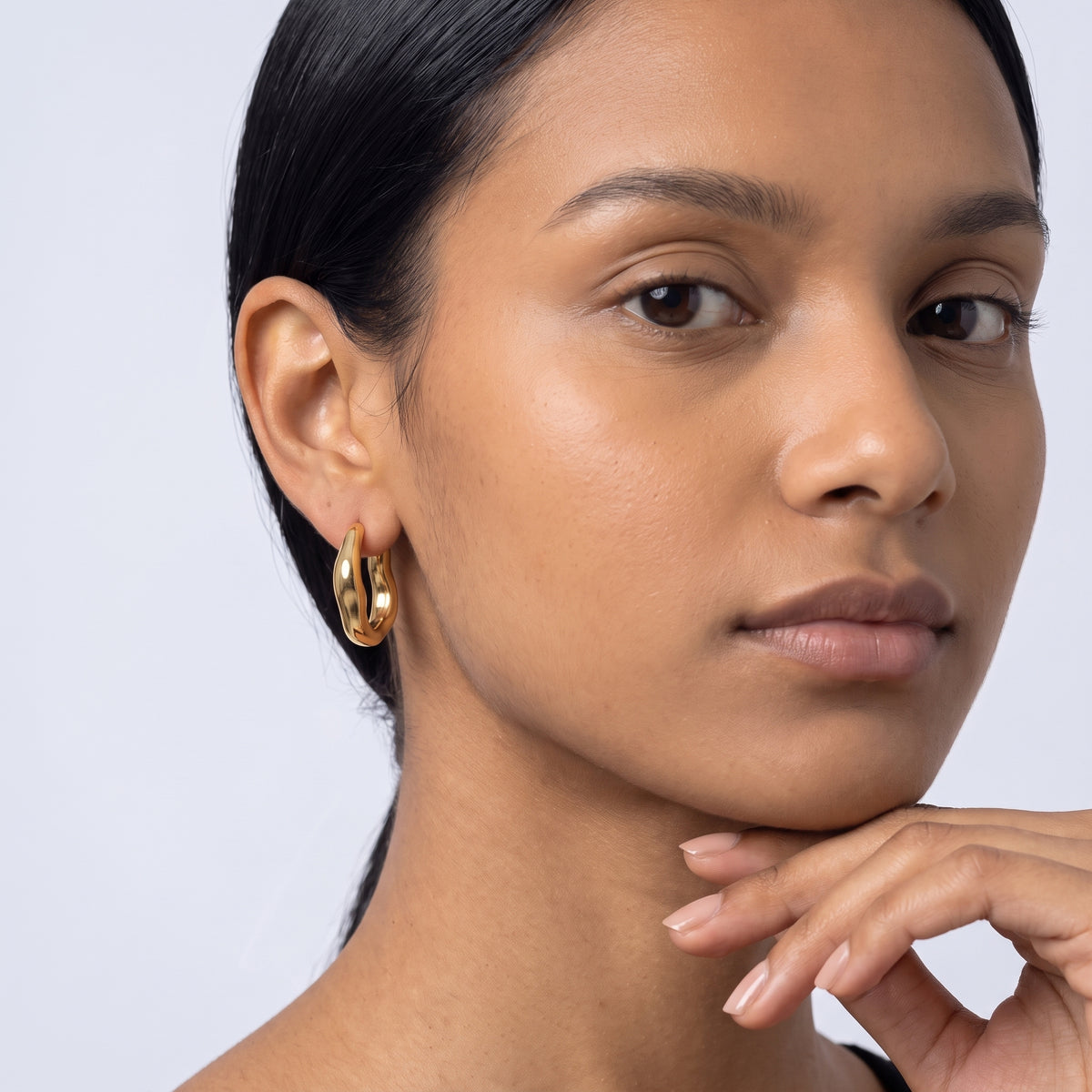 Model wearing the Lelice Maya Hoop Earrings in gold, hand at the chin