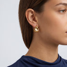 Model wearing the Lelice Maya Ripple Hoops in gold, ear and jaw, slightly wider