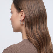 Model wearing the Lelice Maya Ripple Silver Hoops, three-quarter back view