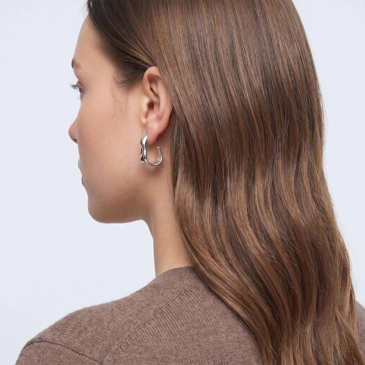 Model wearing the Lelice Maya Ripple Silver Hoops, three-quarter back view