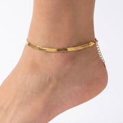 Close-up of the Lelice Mila Herringbone Anklet in gold on a woman's ankle
