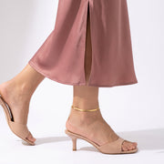 Woman mid-step through a skirt slit wearing the Mila Herringbone Anklet