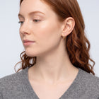 Model wearing the Lelice Molly Hoop Earrings in gold, serene chin lift