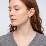 Model wearing the Lelice Molly Hoop Earrings in gold, serene chin lift