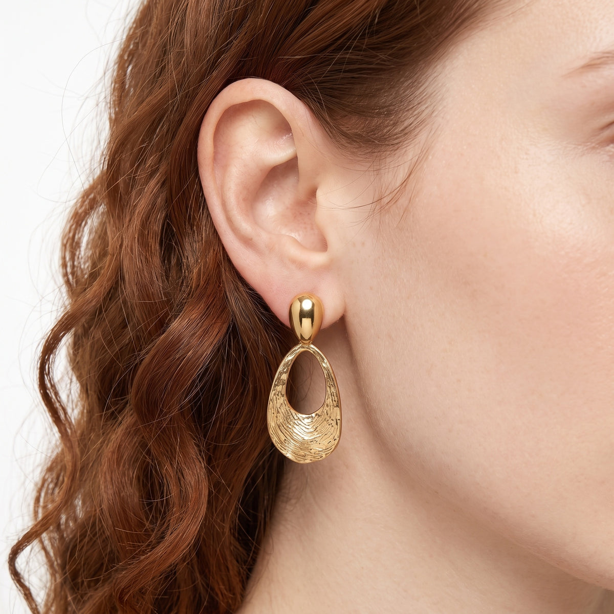 Close-up of the Lelice Nadia Gold Textured Teardrop Statement Earrings on the ear