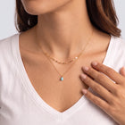 Hand at the collar of a woman wearing the Naxos Opal Necklace