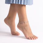 Bare foot on tiptoe wearing the Nia Silver Clover Anklet