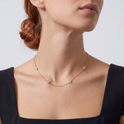 Low-angle portrait of a woman wearing the Noémie Crystal Necklace