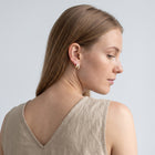 Model wearing the Lelice Odette Pearl Earrings in gold, over-the-shoulder glance