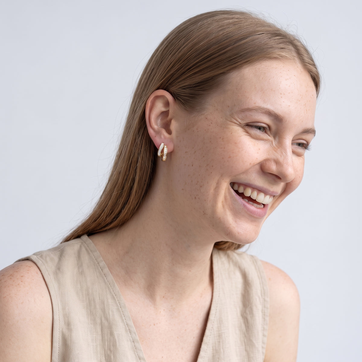 Model wearing the Lelice Odette Pearl Earrings in gold, candid laugh