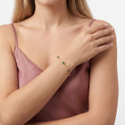 Wrist resting across the body wearing Olive gold emerald bracelet