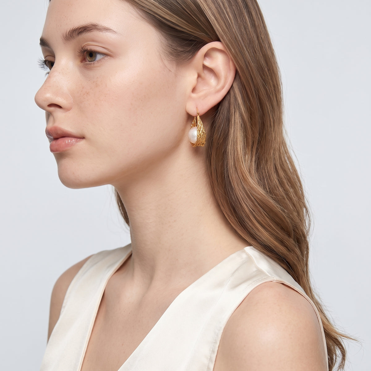 Model wearing the Lelice Pearl Nest Hoops in gold, side profile portrait